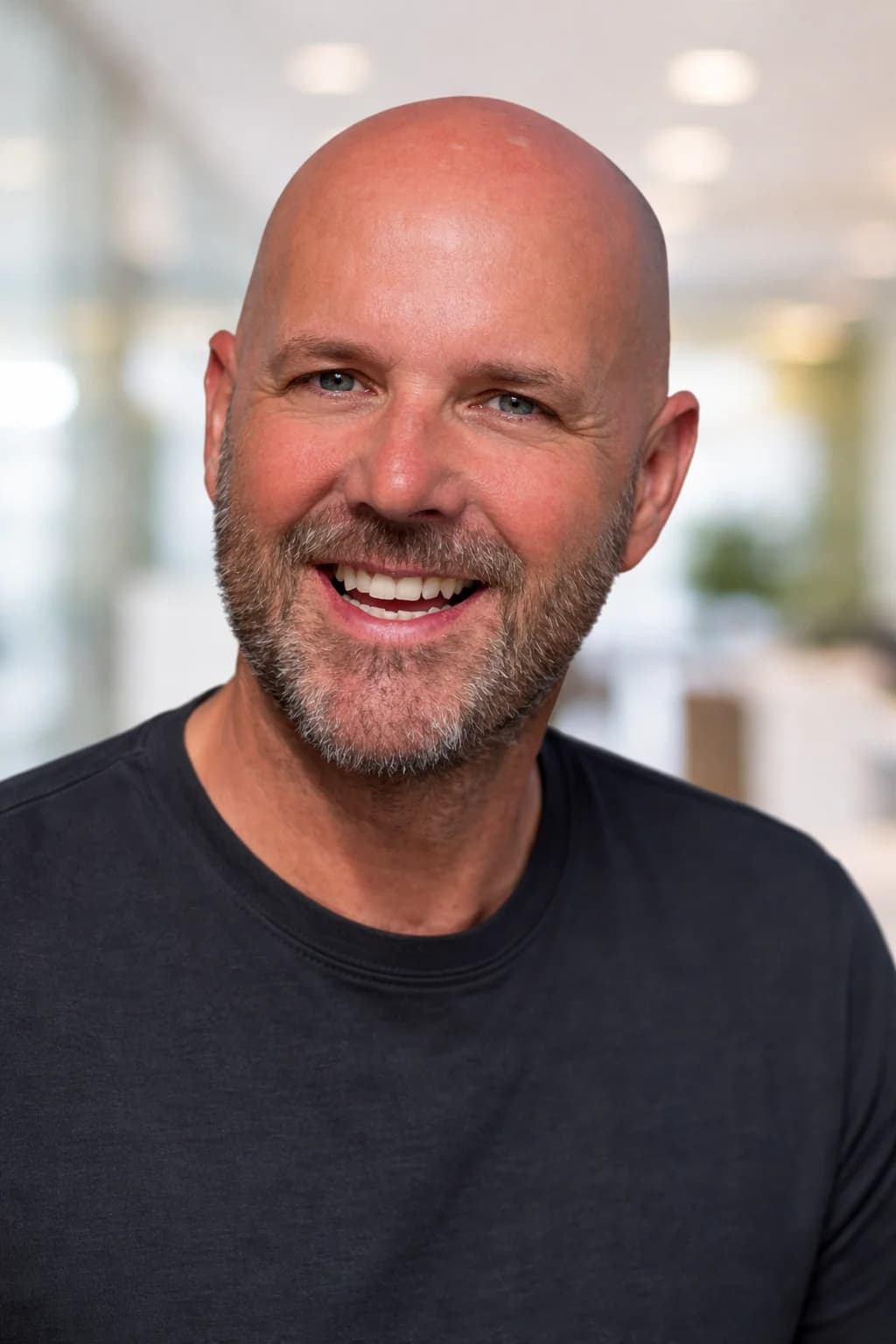 Simon, smiling, in a dark t-shirt against a bright out-of-focus office.
