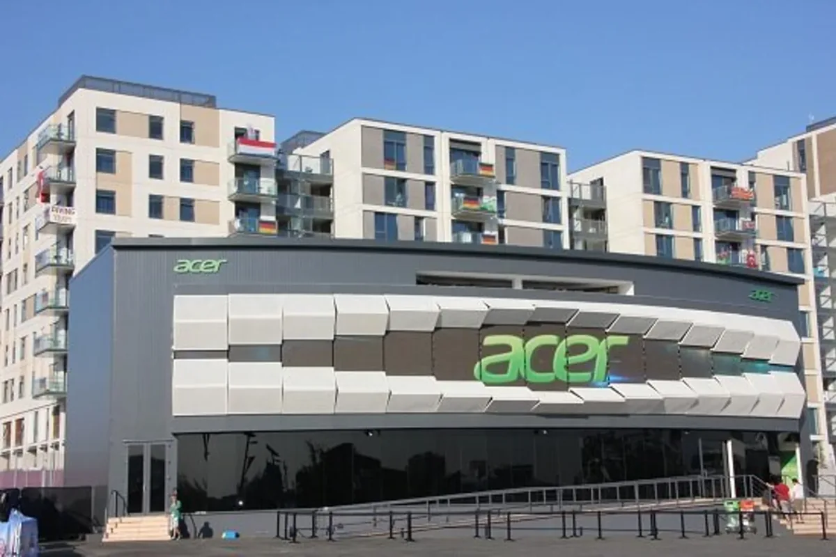 The Acer pavilion at the London 2012 Olympic Park, a low building with a sculpted metal facade and the Acer logo across it.