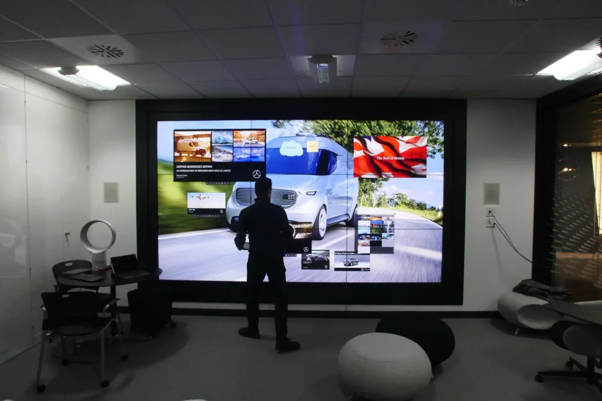 An interactive touchscreen experience for Mercedes-Benz: a person standing at a wall-sized screen showing a van against a landscape.